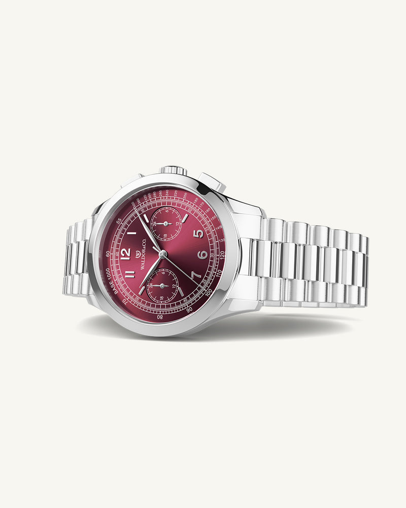 A round mens watch in rhodium-plated silver from Waldor & Co. with a burgundy colored sunray dial and a second hand. Seiko movement. The model is Chrono 39 Porto Cervo.