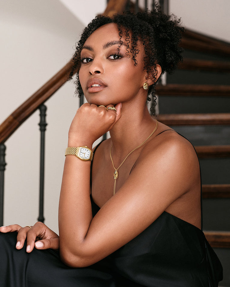 A polished stainless steel ring in 14k gold from Waldor & Co. One size. The model is Dual Knot Ring.