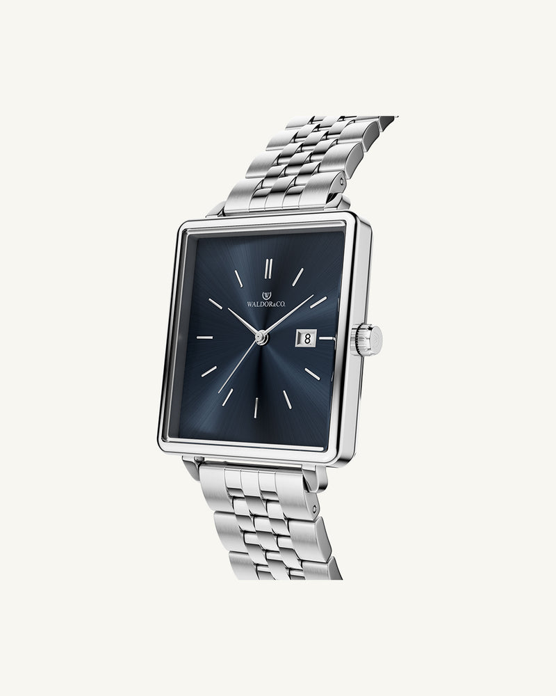 A square womens watch in silver from WALDOR & CO. with blue sunray dial and a second hand. The model is Delight 32 Chelsea 28x32mm.