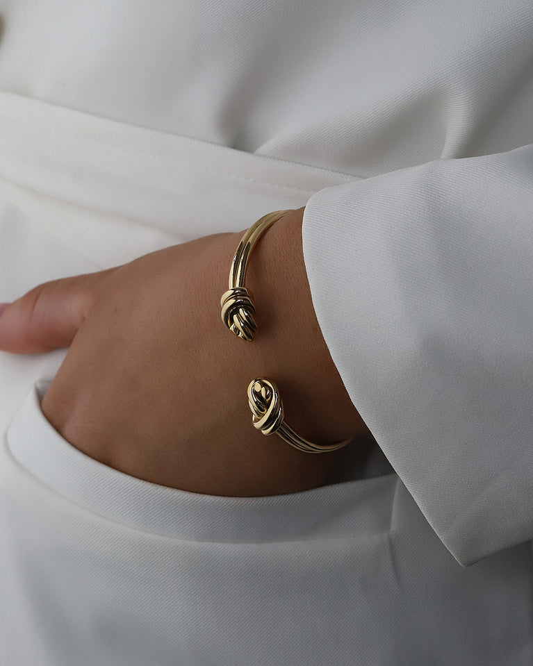 A Bangle in 14k-gold plated 316L stainless steel from Waldor & Co. One size. The model is Dual Knot Twin Bangle Polished.