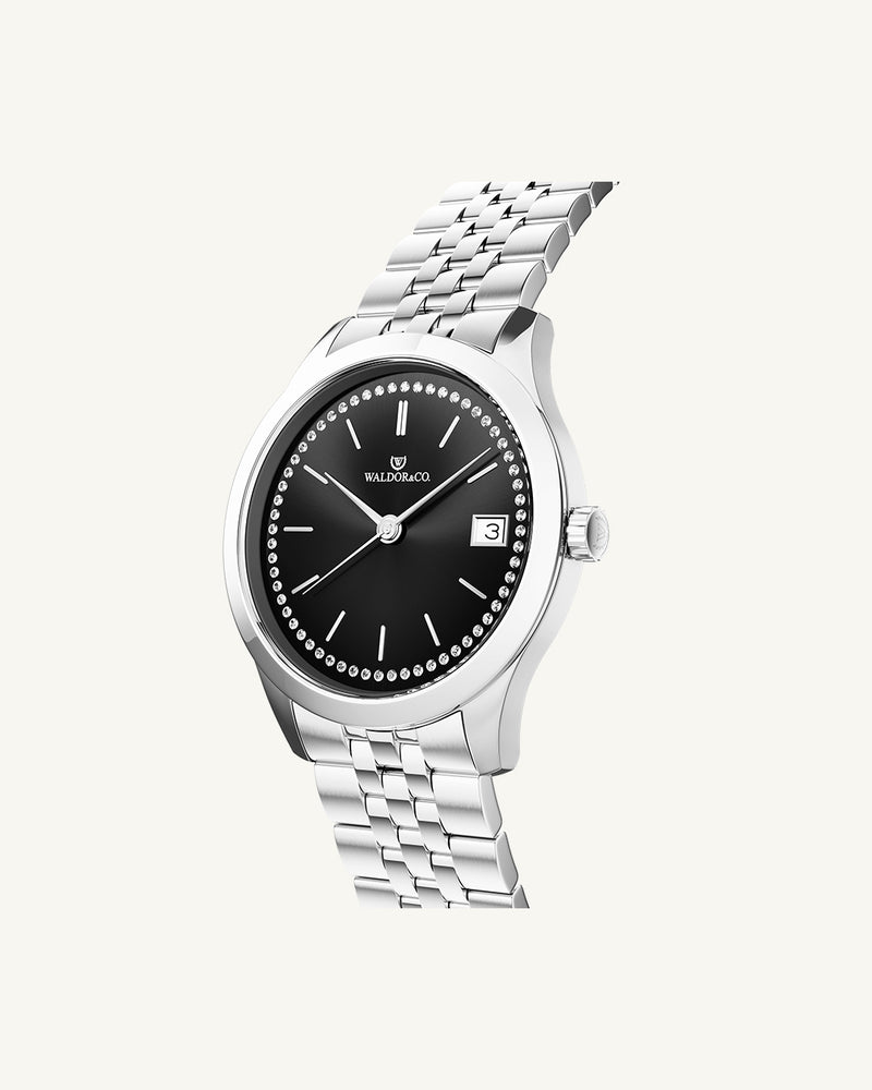 A round womens watch in Rhodium-plated 316L stainless steel from Waldor & Co. with black sunray dial and a second hand. Seiko movement. The model is Imperial 36 Roma 36mm.