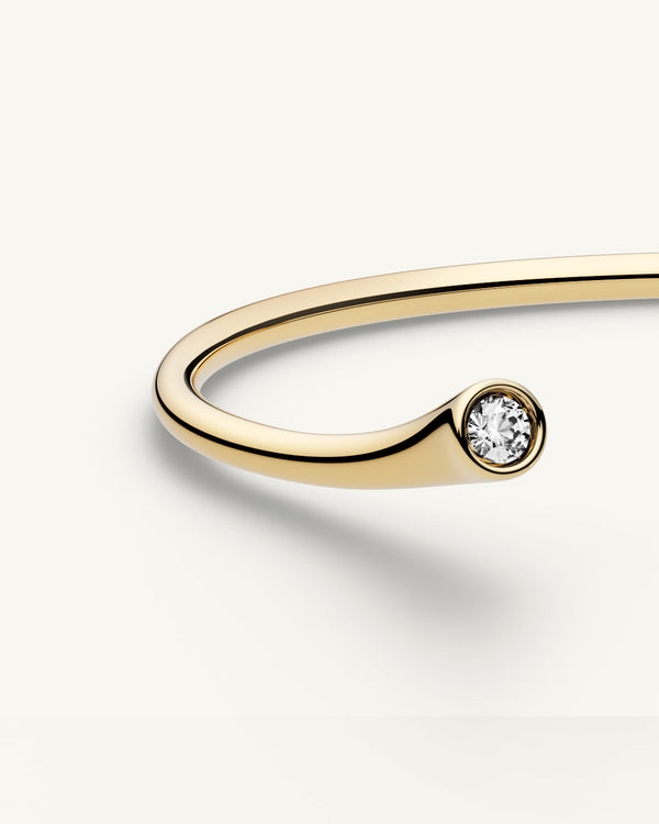 A polished stainless steel bangle in 14k gold from Waldor & Co. One size. The model is Delight Bangle.