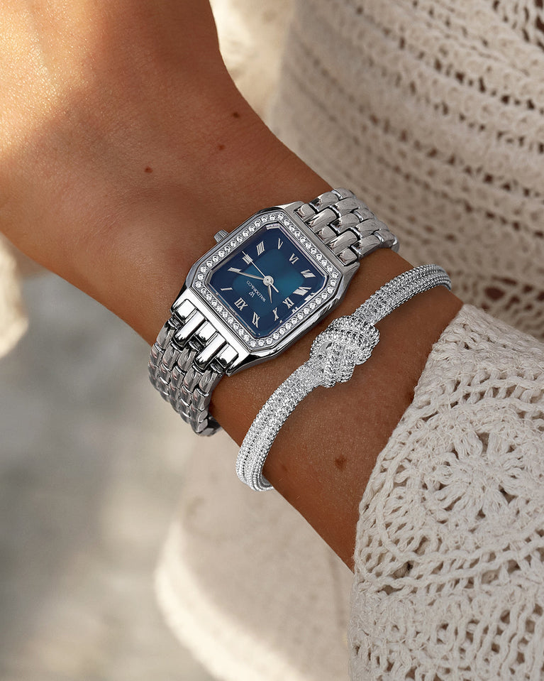  A square womens watch in Rhodium-plated 316L stainless steel from Waldor & Co. with dark blue dial. Bezel with premium crystals. Diamond Cut Sapphire Crystal glass dial. Seiko movement. The model is Eternal 22 Bellagio Pavè.