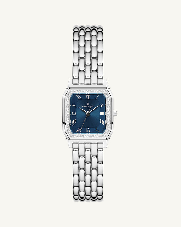A square womens watch in Rhodium-plated 316L stainless steel from Waldor & Co. with dark blue dial. Bezel with premium crystals. Diamond Cut Sapphire Crystal glass dial. Seiko movement. The model is Eternal 22 Bellagio Pavè.