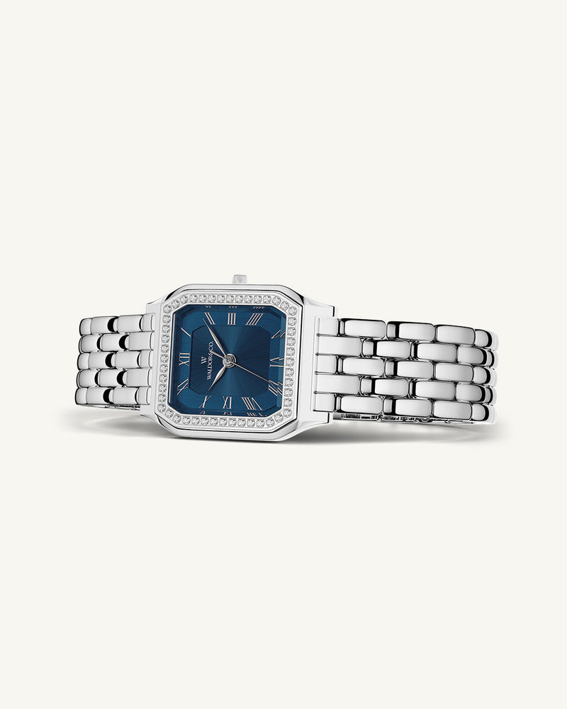 A square womens watch in Rhodium-plated 316L stainless steel from Waldor & Co. with dark blue dial. Bezel with premium crystals. Diamond Cut Sapphire Crystal glass dial. Seiko movement. The model is Eternal 22 Bellagio Pavè.