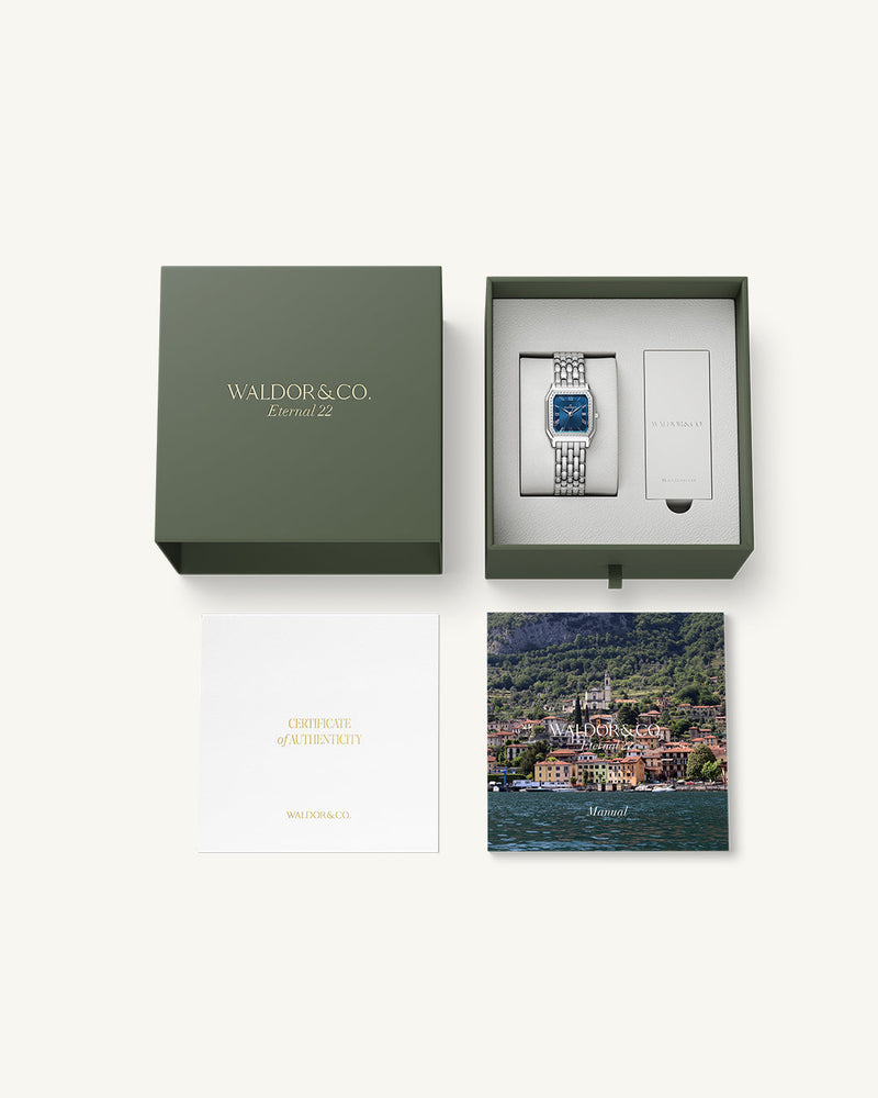 A square womens watch in Rhodium-plated 316L stainless steel from Waldor & Co. with dark blue dial. Bezel with premium crystals. Diamond Cut Sapphire Crystal glass dial. Seiko movement. The model is Eternal 22 Bellagio Pavè.